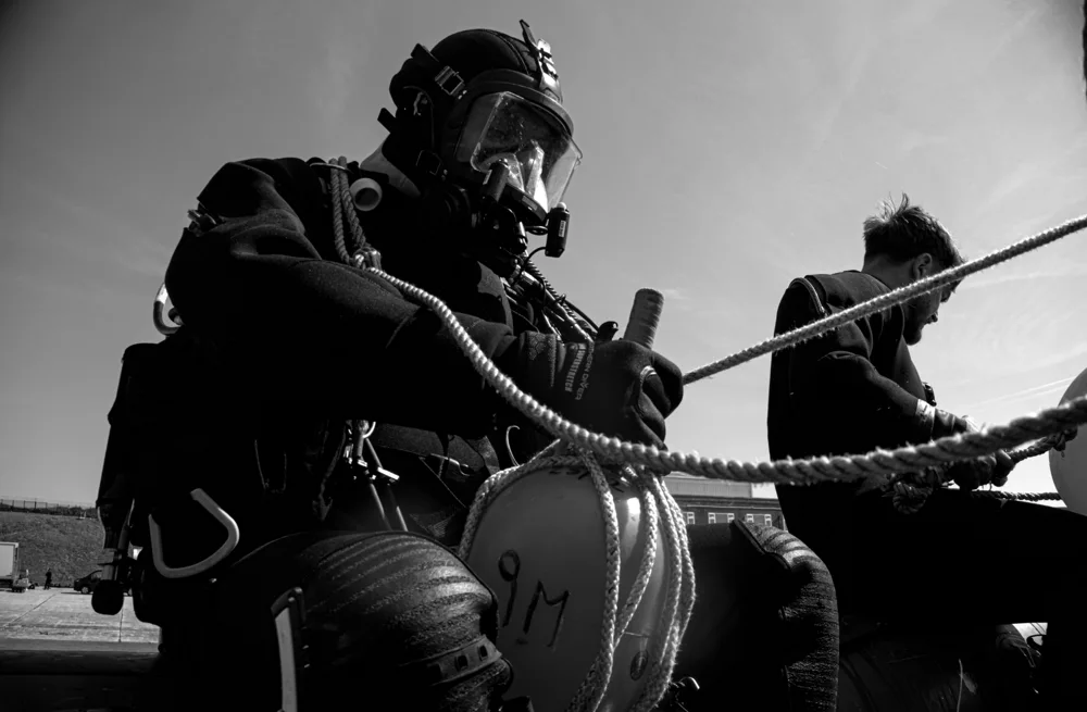 Diver checking equipment and rope aboard a boat